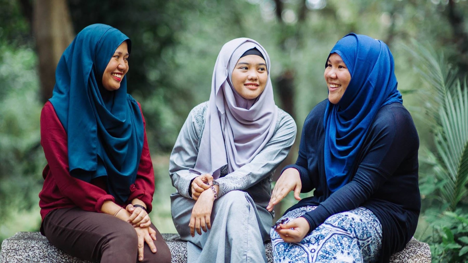Three young women chat and laugh together outdoors.
