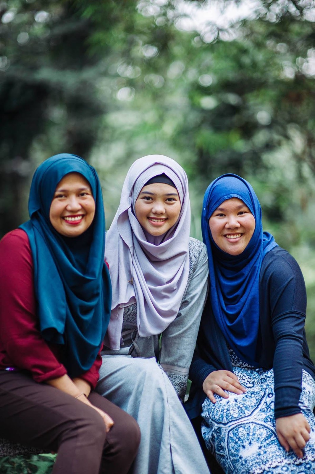 Three young women smile together for a portrait.