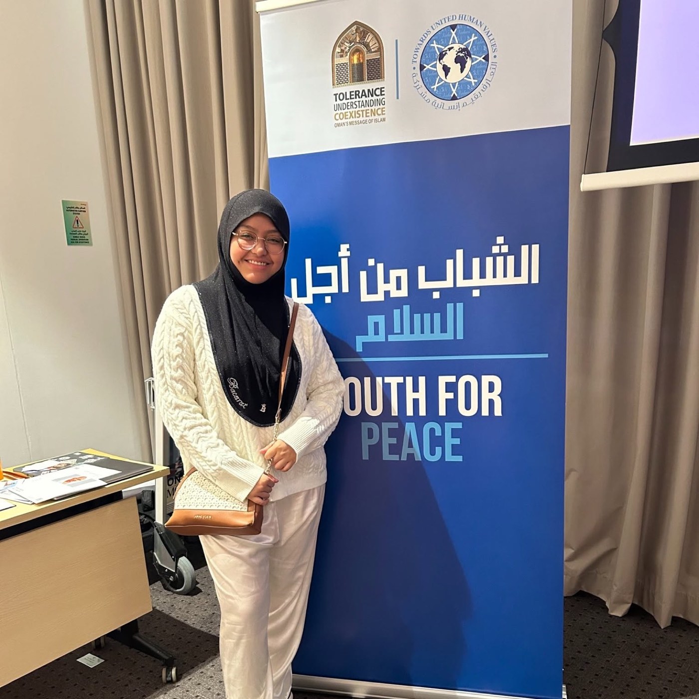 A young leader stands beside a Youth for Peace banner at a regional gathering.