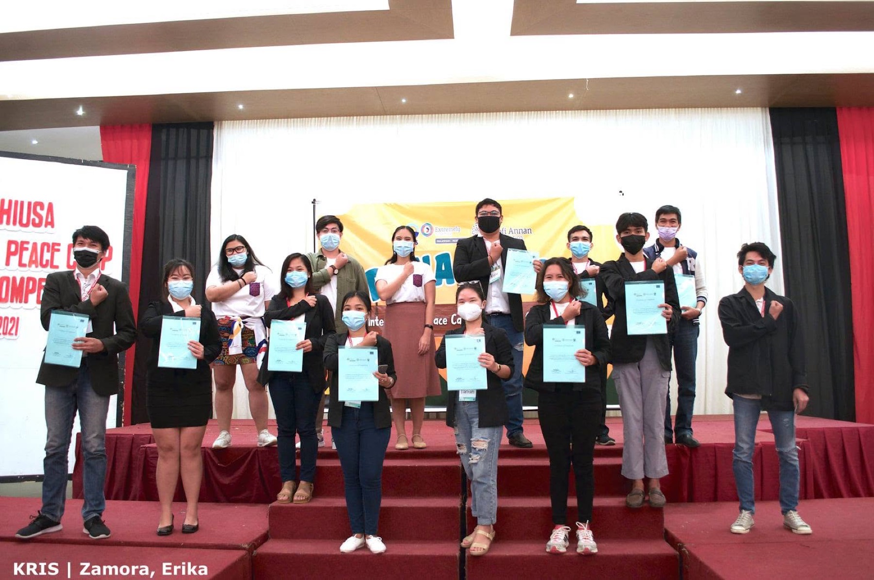 Grant recipients raise a fist to their chest while holding certificates.