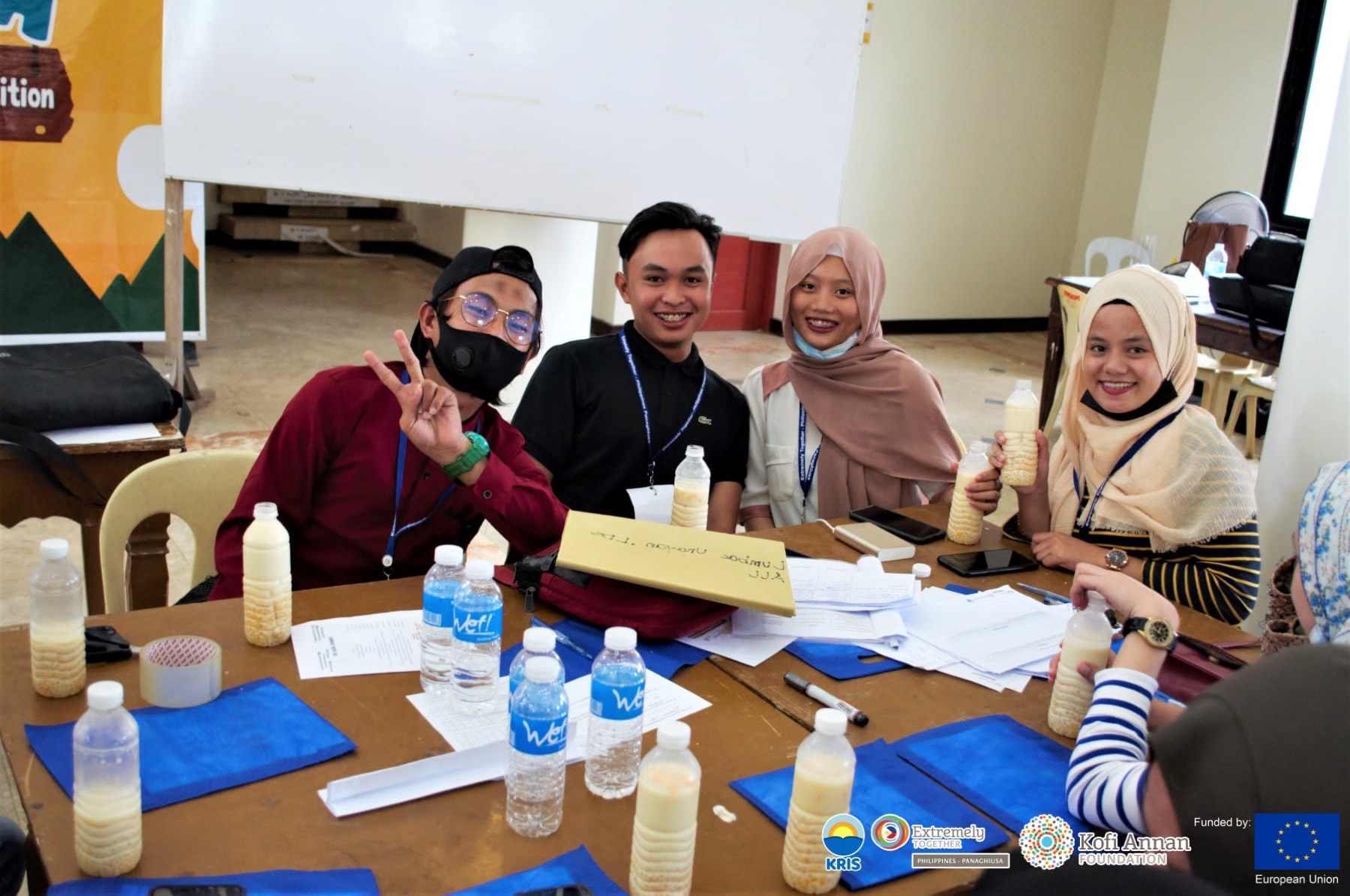 Four peace camp participants smile together at a workshop table.